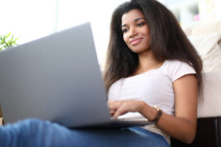 Low angle of latino american young female surfing on internet. Smiling cheerful lady searching for...