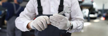 Close-up view of male specialist showing mechanical tool for fixing automobiles. Service station and car maintenance concept. Special professional equipment for garage workerの写真素材
