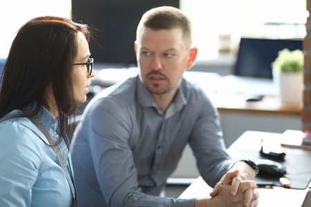 A man and a woman are sitting at a table in the office. Employees discuss work processes in the workplaceの写真素材