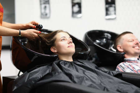 A married couple at the hairdresser washes their hair before a haircut. Hairdresser is washing the hair of a young womanの写真素材