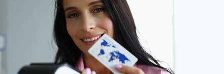 Close-up of beautiful businesslady offering to pay cashless payment. Smiling businesswoman looking...