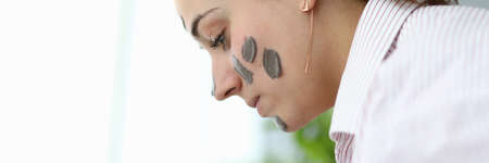 Close-up of young female with clay mask on face. Attractive woman in pyjamas after night sleep. Copy...