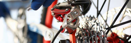 Close-up of mechanic serviceman installing assembling or adjusting bicycle gear on wheel in...