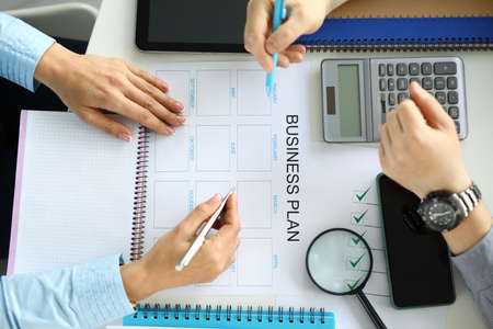 People sit at the table and make a business plan on paper. Profit and loss calculation during quarantineの写真素材
