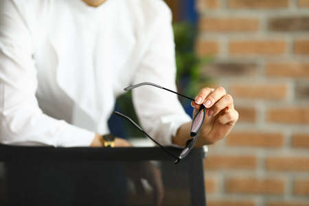 Business woman in a white blouse holds glasses for vision. Woman heads the departmentの写真素材