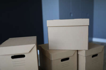 Cardboard boxes stand near the front door of the room. Arrange a move to a new office. Furniture and items packagingの写真素材