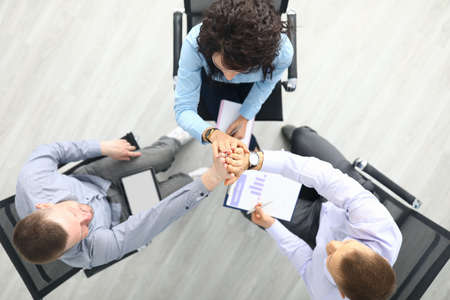 Man and woman sit on chairs and join hands in agreement and unityの写真素材