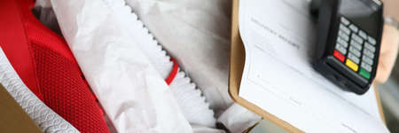 Courier holds running shoes and portable terminal. Delivery order sneakers by courier during...