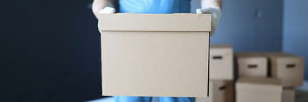 Man in work clothes is standing in office with box. Successfully remove all items from home. Box reliably protects transported things from environmental influences. Moving to new officeの写真素材