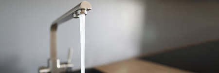 Close-up of kitchen faucet and water pressure in new modern apartment. Cropped picture of domestic...