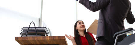 Low angle of business partners celebrating contract. Male employee holding clipboard with paper and...