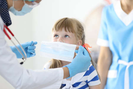 Female doctor with little child put on protective mask portrait. Disease prevention concept