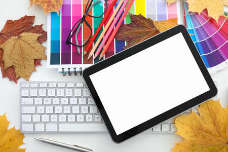 On table there is a keyboard with tablet, glasses autumn leaves and colored polish. Designer services conceptの写真素材