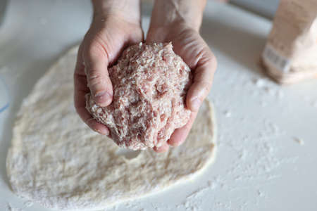 Male hands hold minced meat on background of dough. Cooking recipes conceptの写真素材