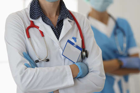 Two doctors in gloves and white coats stand with folded arms. Modern approach to the education of doctors conceptの写真素材