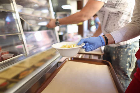 Female hand in glove holds plate of salad in cafe. Catering in the corona virus conceptの写真素材