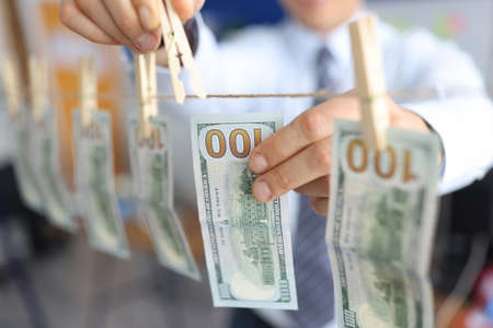 Mans hand hangs one hundred dollar bills on clothespin. Investment in the economy and business...
