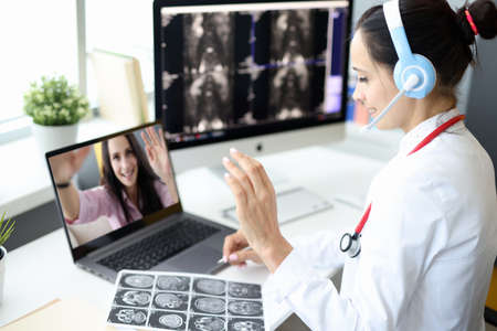 Medical employee operator in headphones with microphone greets the hand of interlocutor. Doctors...