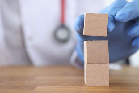 Medical officer constructs tower from wooden blocks. Doctor career growth concept