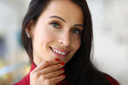 Portrait of smiling brunette woman with red manicure. Beauty salon services conceptの写真素材