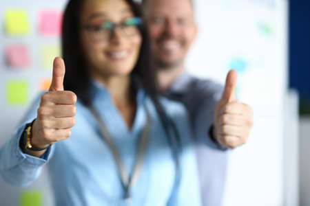Businesswoman and businessman hold thumbs up and smile. Successful business planning concept
