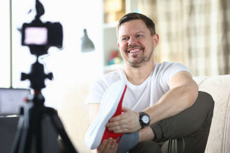 Male blogger makes video review on camera on topic of sneakers. Online shopping concept