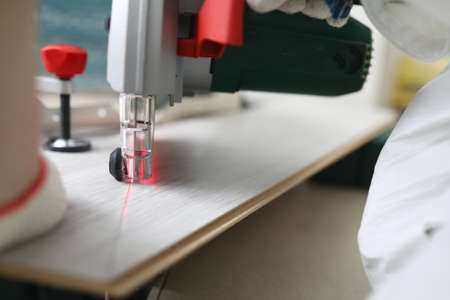 Master cuts laminate with laser cutting machine. Floor covering installation services concept
