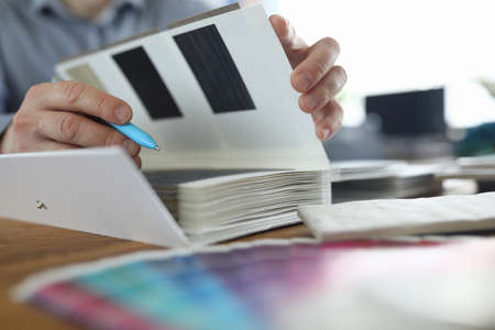 Male hands are holding pen and samples of finishing materials. Services of interior designers...