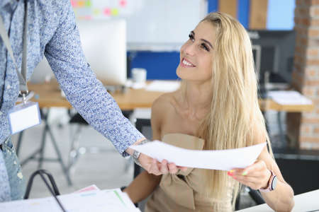 Businesswoman smiles at her colleague and birches his document. Positive communication between business partners conceptの写真素材