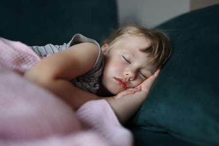Little girl sleeps in bed with her arms folded under her head. Childrens fantasies and dreams...