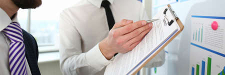 Portrait of smart people discussing contract conditions. Young man pointing at paper folder and...