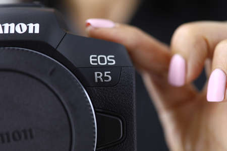 Minsk, Belarus - 30 July 2020 : female hand holding a camera canon eos r5 closeup . Illustrative...