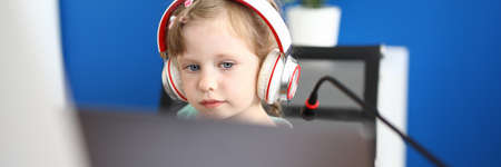 Little girl work with laptop against home background. Online school education concept.の写真素材