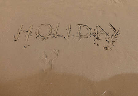 Word leave and footprints write on sand. Coast of soft sand and sea waves.の写真素材