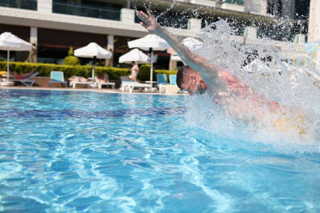 Man swim with breast stroke in blue pool of clear water. Splashes of water fly to sides.の写真素材
