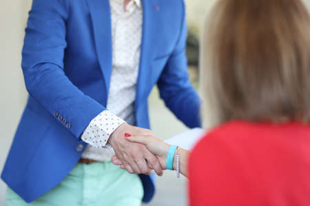 Man in blue jacket shake hands with woman. Acquaintance and partnership in business.