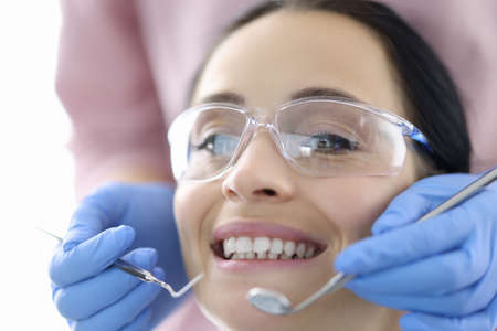 Young woman at dentists office with instruments in her hands. Dental treatment and prosthetics concept.の写真素材