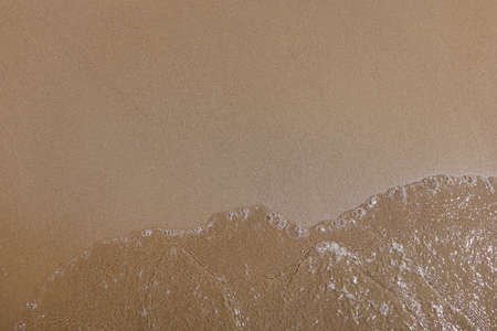 Sea wave on shore. Smooth fine sand and clear water with bubbles.