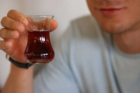 Mans hand holds glass of dark liquid in his hands. Treatment for alcoholism conceptの写真素材