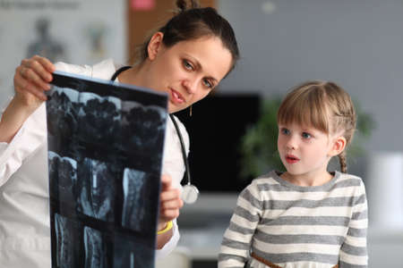 Woman doctor shows child patient an xray in clinic. Use of radiation diagnostics of diseases of...