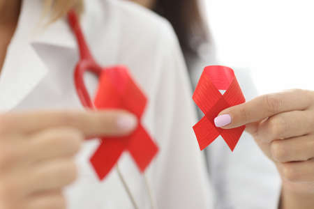 Doctors in white coats hold red ribbon in their hands. Methods for diagnosing HIV infection conceptの写真素材