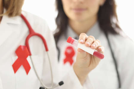 Doctors in white coats are holding test tube of blood. HIV infection diagnosis and treatment conceptの写真素材