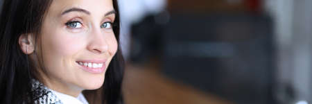 Portrait of smiling beautiful young woman sitting in office. Pretty employee in stylish costume. Copy space in right side. Businesswoman with charming appearance. Business and economy conceptの写真素材