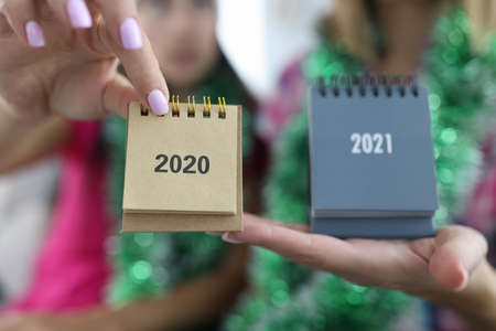 Female hands holding calendars 2020 and 2021 closeup. Production and printing of desktop calendars...