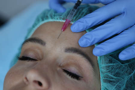 Portrait of woman who gets an injection between her eyebrows. Eyebrow injections for wrinkle removal...