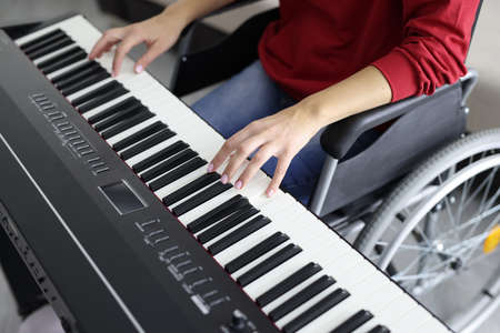 Woman in wheelchair plays synthesizer. Music lessons for people with disabilities conceptの写真素材