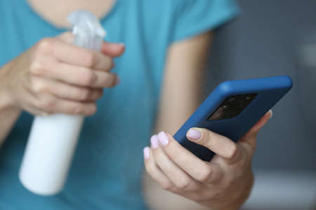 In hand smartphone is being sprayed with an antiseptic. Dangerous bacteria on mobile phone conceptの写真素材