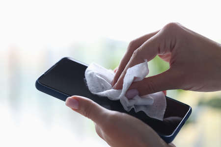 Smartphone in hand, which is wiped with a damp cloth Dangerous bacteria on mobile phone in coronavirus pandemic conceptの写真素材