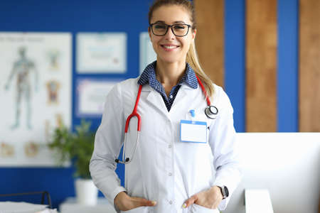 Female doctor in white coat stands in medical office. Medical assistance to the injured conceptの写真素材