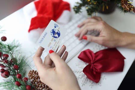 In hands of plastic bank card next to New Years decoration keyboard. New Year sales in online stores around the world conceptの写真素材